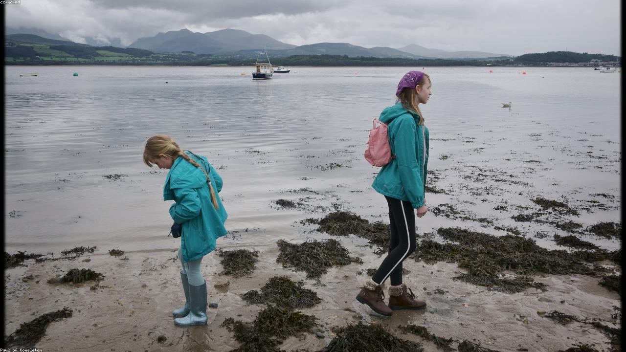 Beaumaris seafront with the medieval castle and the Snowdonia mountains reflected in the Menai Strait