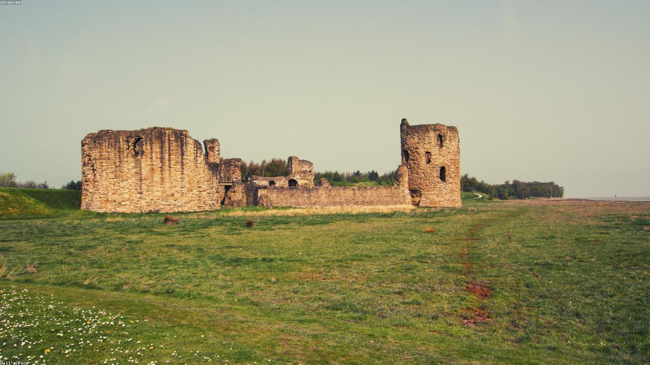 Flint Castle ruins on the Dee Estuary shore at low tide with the Welsh hills behind