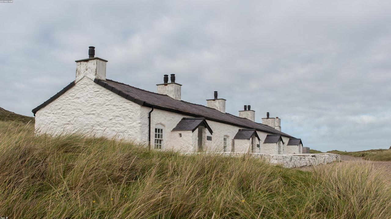 Llanddwyn Island lighthouse Tŵr Mawr on Ynys Llanddwyn Anglesey with beach and mountains