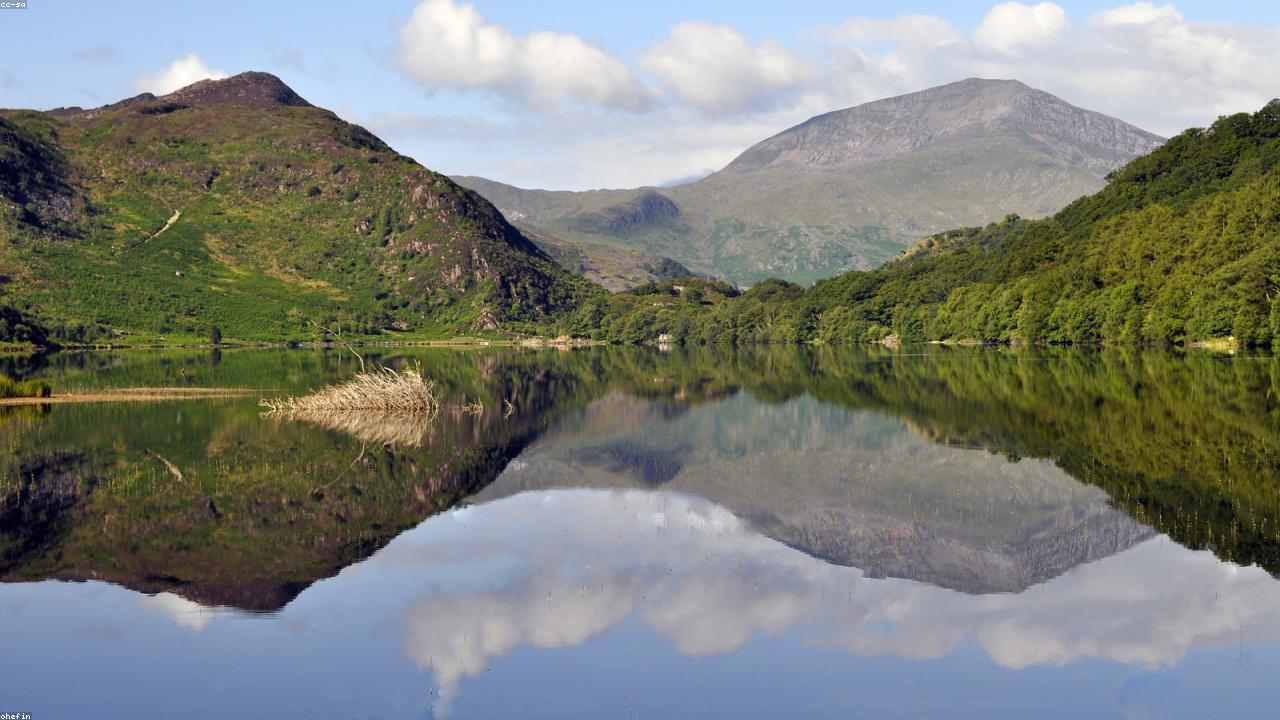 Llyn Dinas lake in Nantgwynant with Dinas Emrys hillfort above and the Snowdon ridgeline beyond